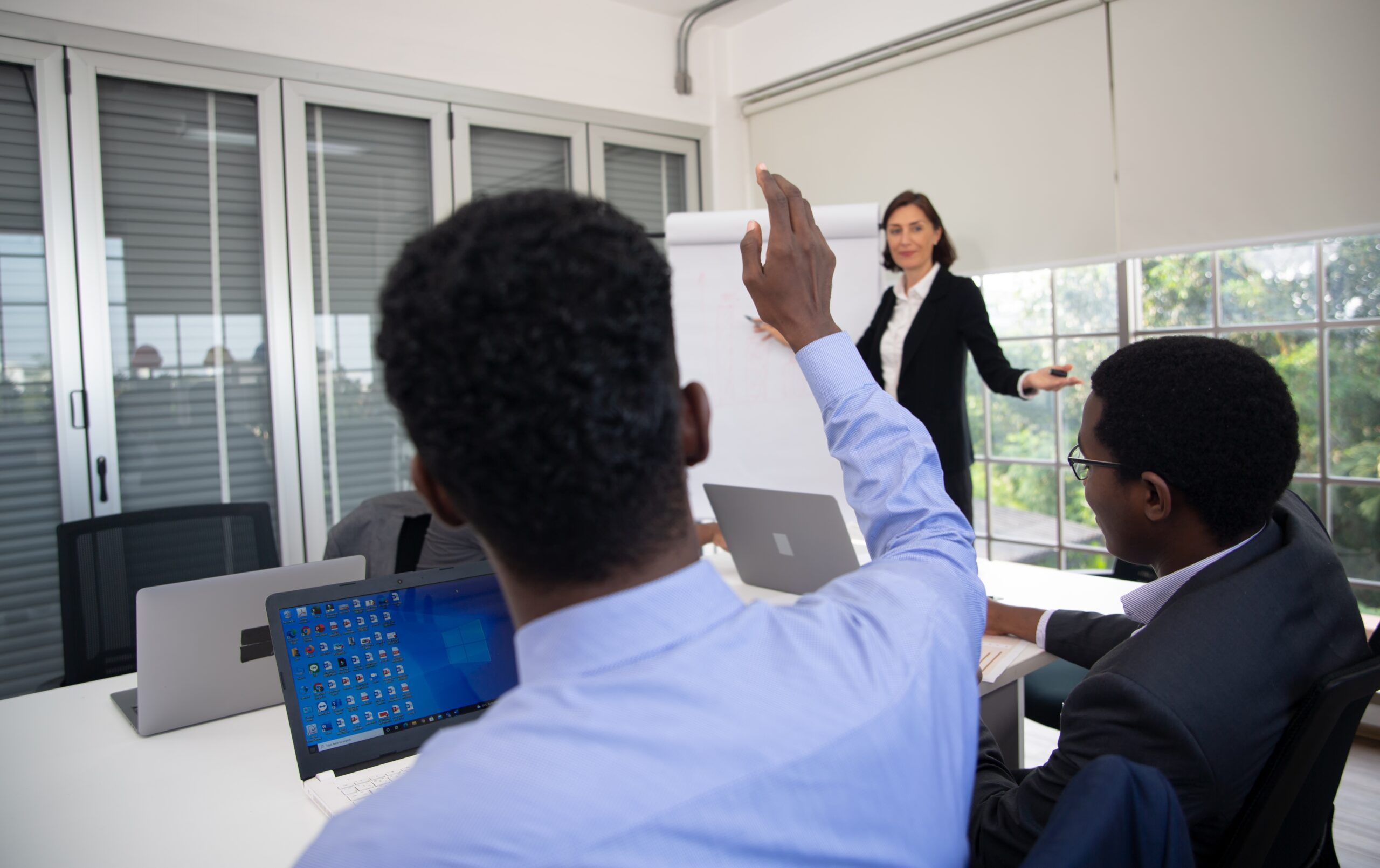 pexels-rodnae-productions-7414041 Group of people in a meeting room, with one person presenting and others engaged in discussion.