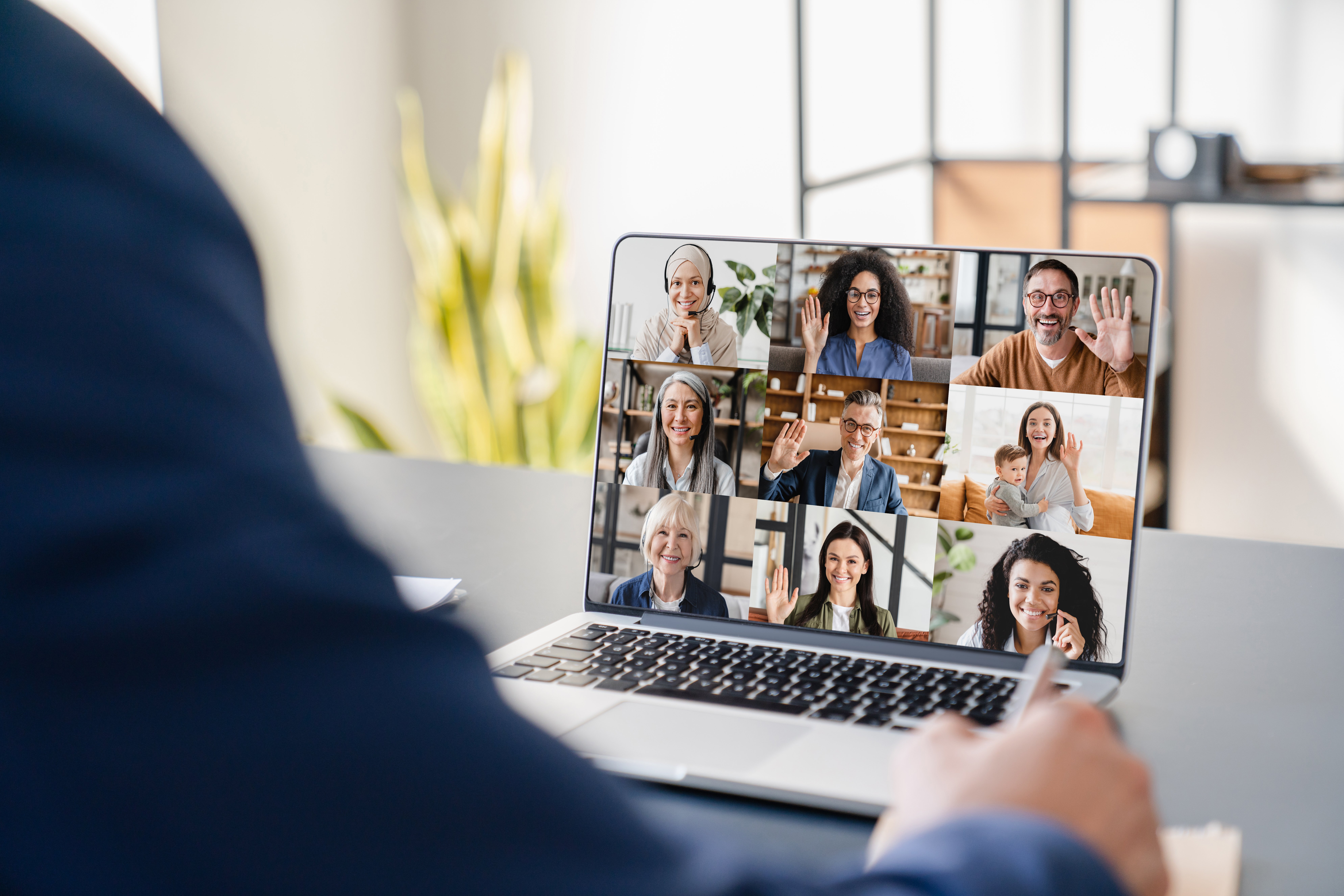 Person attending a video conference call with multiple participants on a laptop screen