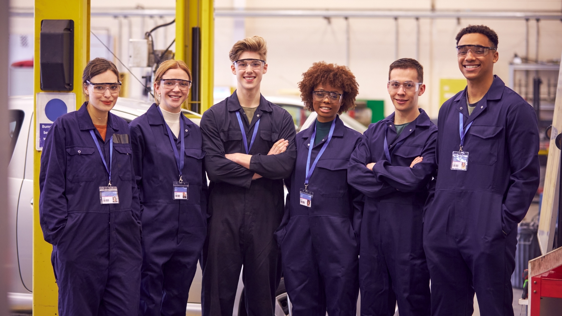 Group of engineers in blue coveralls and safety glasses in a technical workspace