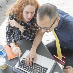 businessman and woman using laptop at cafe table