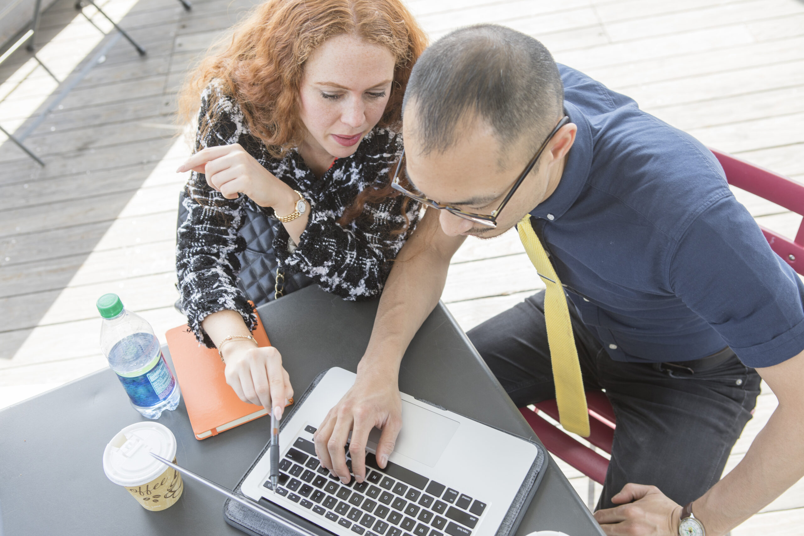 businessman and woman using laptop at cafe table