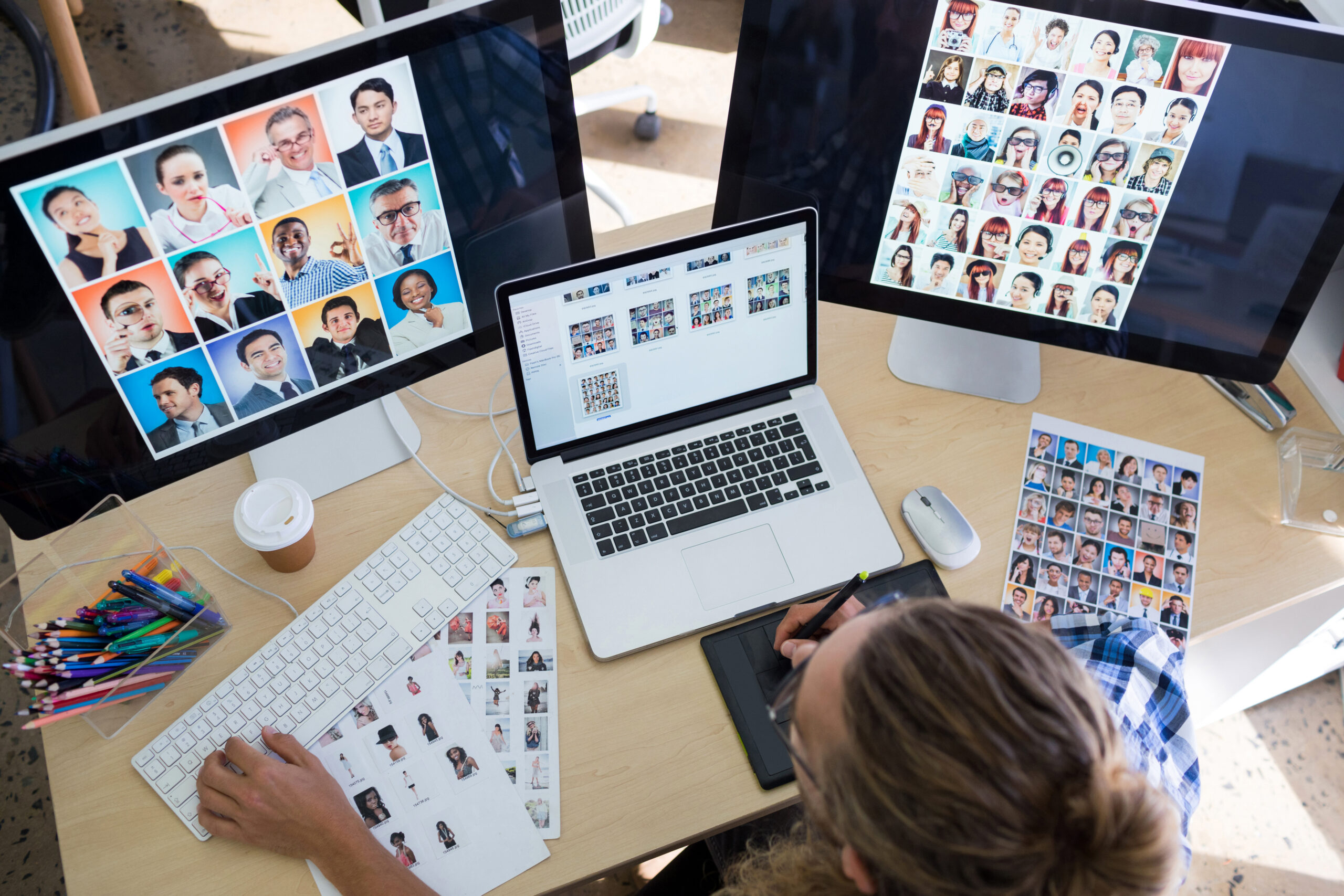 Group of six people sitting together, smiling and looking at a laptop screen in a casual setting, representing digital technology and collaboration.