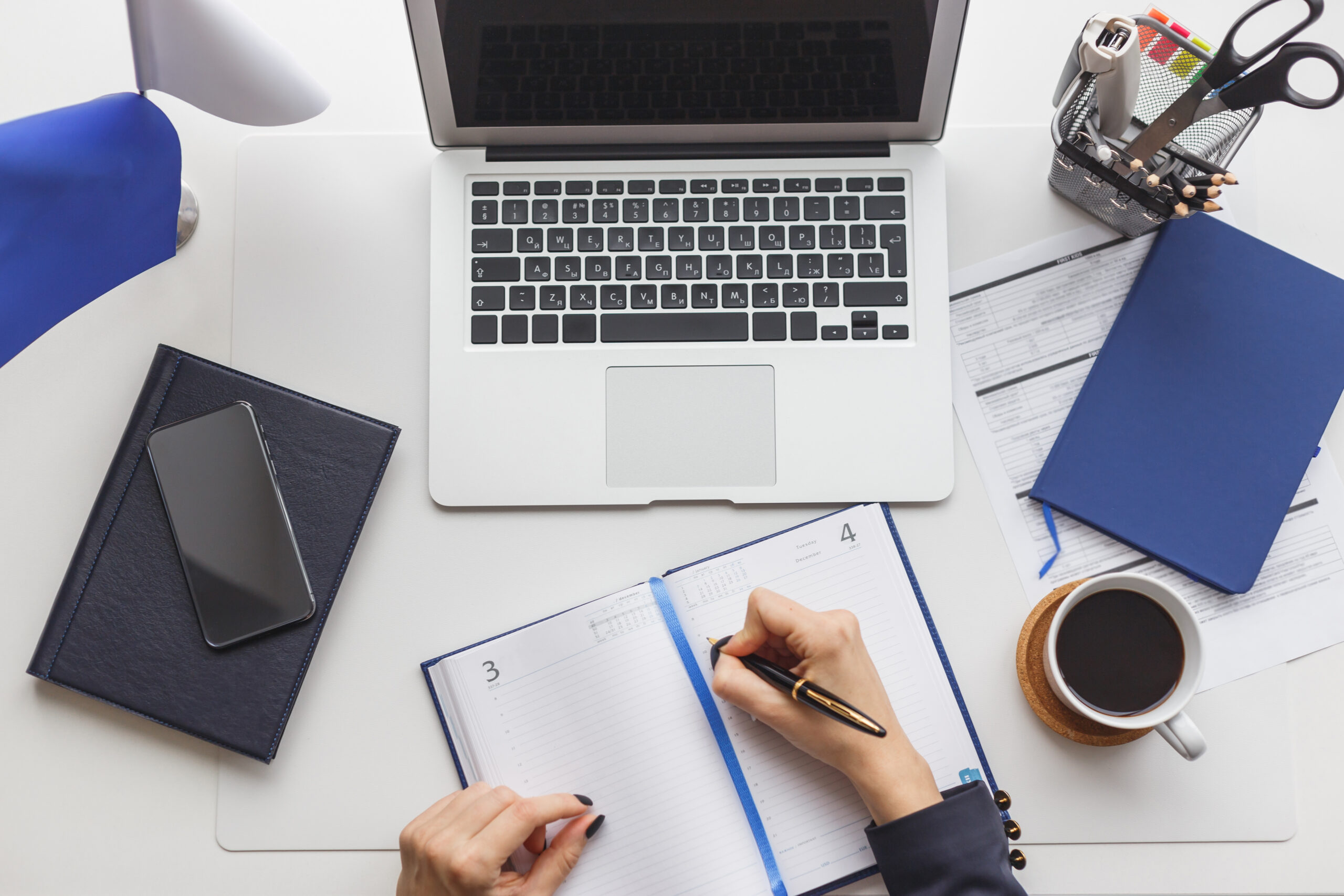 work station with laptop and notepad and hands writing policy notes