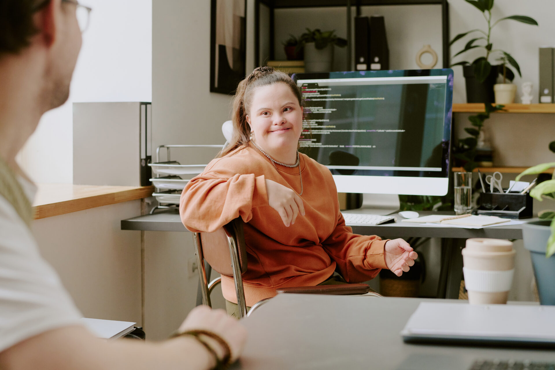 female programmer with down syndrome looking away from computer at her coworker
