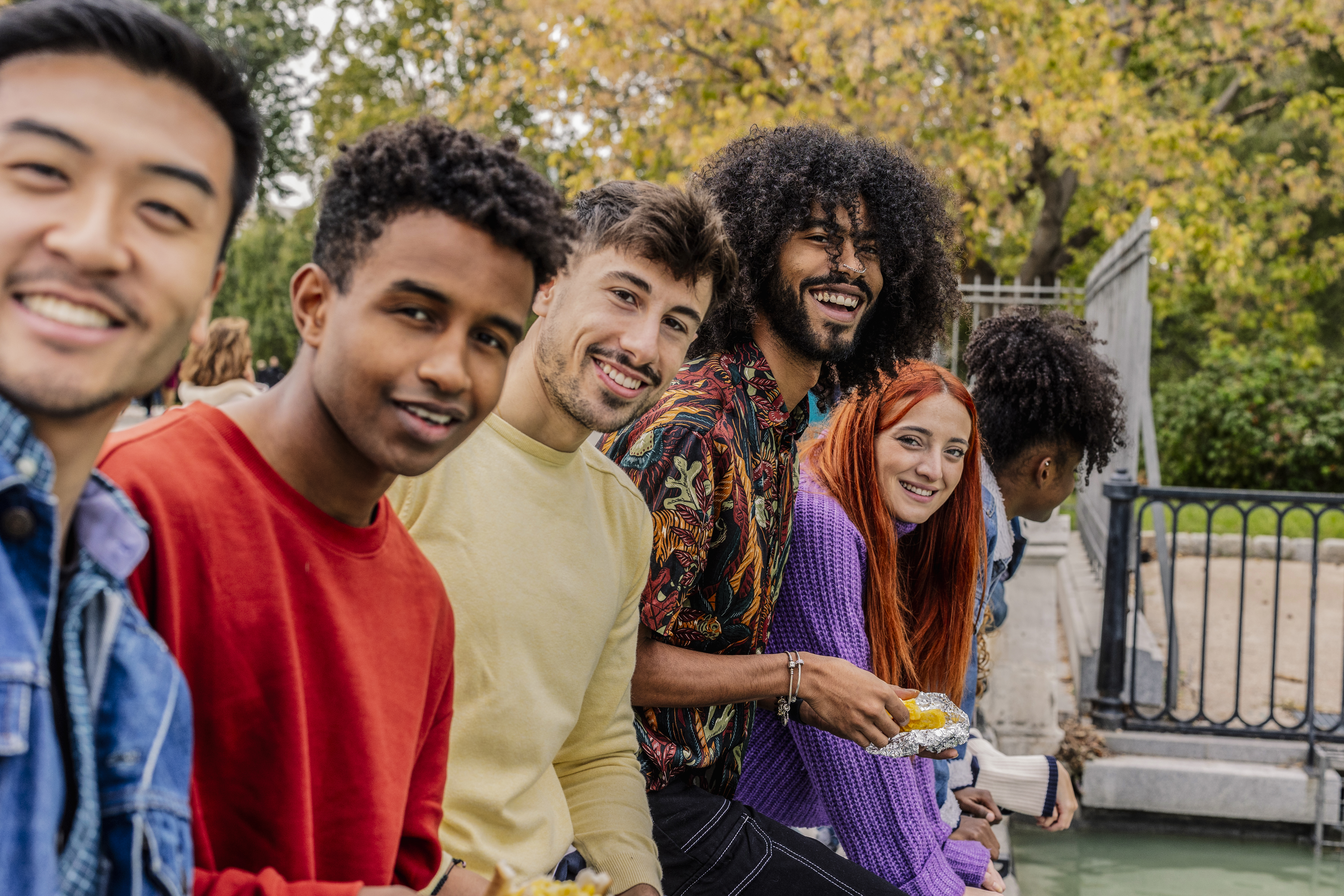 smiling-group-of-friends-eating-outdoors-by-water