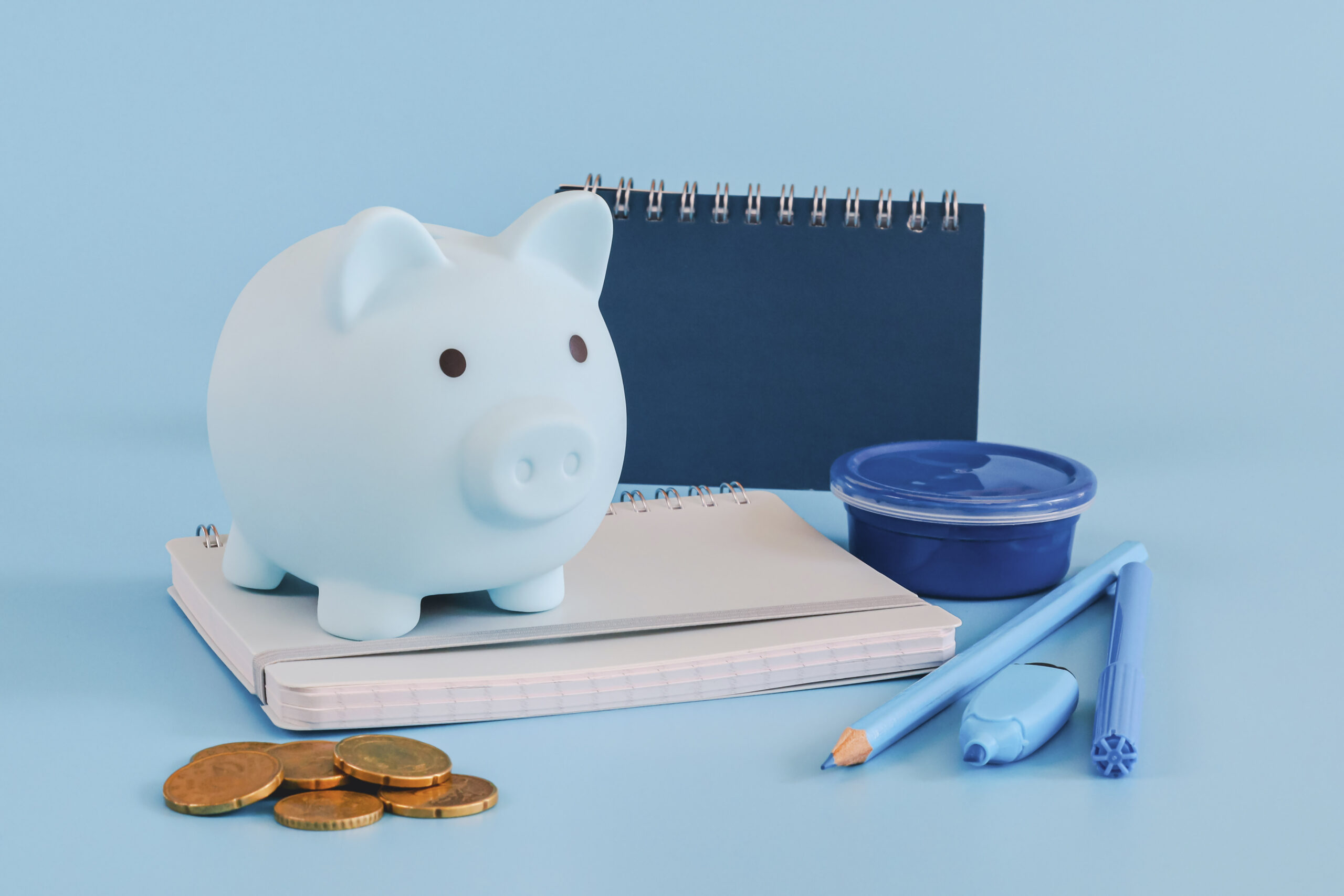 Piggy bank and school supplies on blue background