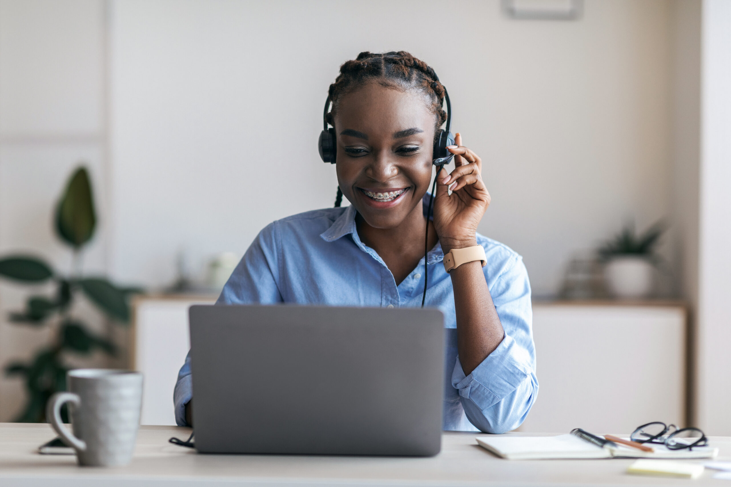 a black, female manager wearing a headset and using a laptop for a live, online training session
