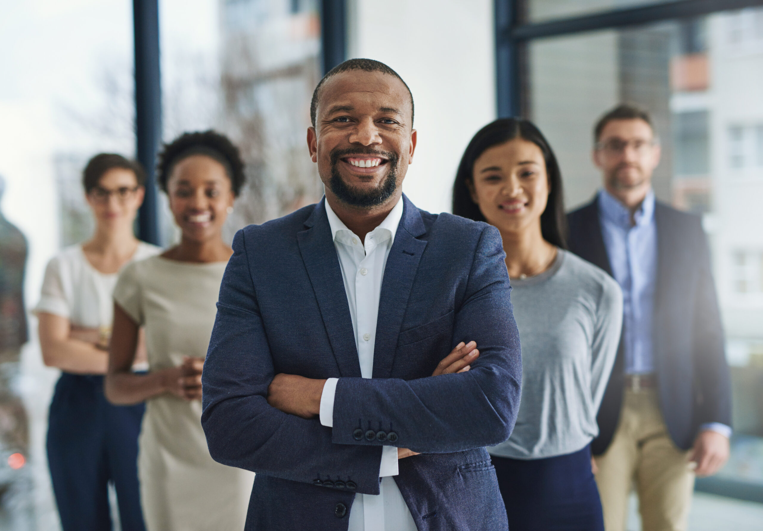 A group of diverse leaders and managers looking towards the camera, standing and smiling.